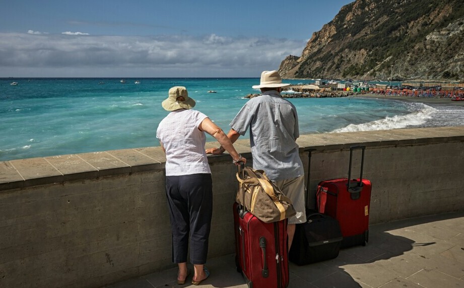 a man and woman holding hands and standing by a wall with luggage